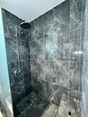 a bathroom with a shower with a stone tile wall at Villa Mike in Rhodes Town