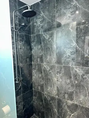a bathroom with a shower with a stone wall at Villa Mike in Rhodes Town
