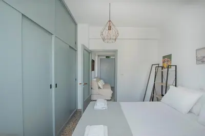 a white bedroom with a bed and a couch at Mandilara Minimal Apartment in Rhodes Town