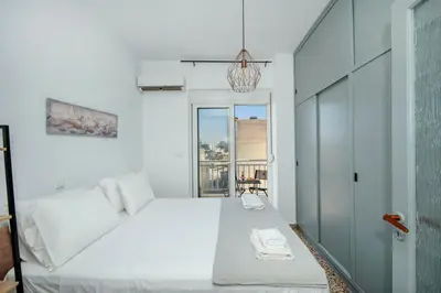 a bedroom with a white bed and a window at Mandilara Minimal Apartment in Rhodes Town