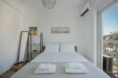 a white bedroom with a large bed with two towels at Mandilara Minimal Apartment in Rhodes Town