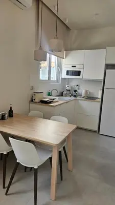 a kitchen with a wooden table and white cabinets at OASIS Central 007 in Rhodes Town