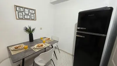 a small kitchen with a table and a refrigerator at Val & Rin Luxury Apartment in Rhodes Town