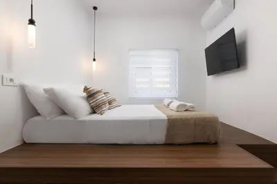 a white bedroom with a bed and a television at Icarus Residence in Rhodes Town