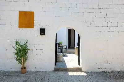 a white brick wall with an archway next to a table at Icarus Residence in Rhodes Town