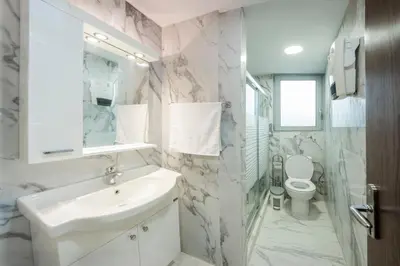 a white bathroom with a sink and a toilet at Magical House in Ialyssos