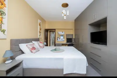 a bedroom with a large white bed and a television at Magical House in Ialyssos
