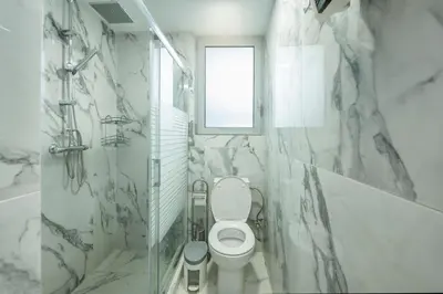 a white bathroom with a toilet and a window at Magical House in Ialyssos