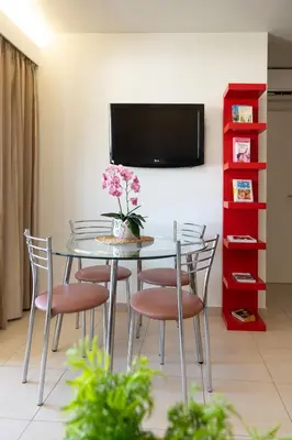a dining room with a glass table with chairs and a tv at Fiore D'oriente Apartments in Rhodes Town