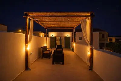 a balcony with chairs and lights at night at Villa Emerald in Koskinou