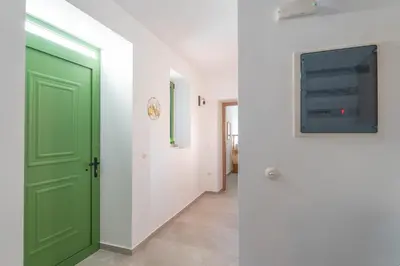 a corridor with a green door and a hallway with white walls at Villa Emerald in Koskinou