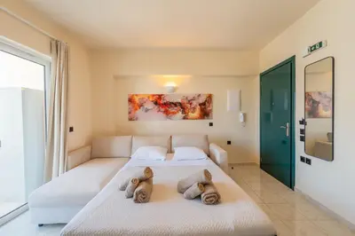 a bedroom with a white bed with two stuffed animals on it at Irem's sunrise suite! in Rhodes Town