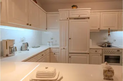 a white kitchen with white appliances and white cabinets at Makiaris Villa in Archangelos