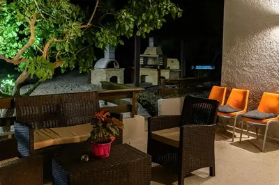 a patio with chairs and a table and a fireplace at Sinani Villa - Garden Oasis with Private Pool in Kolimbia