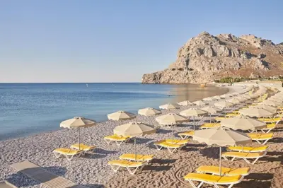 a group of chairs and umbrellas on a beach at Sinani Villa - Garden Oasis with Private Pool in Kolimbia