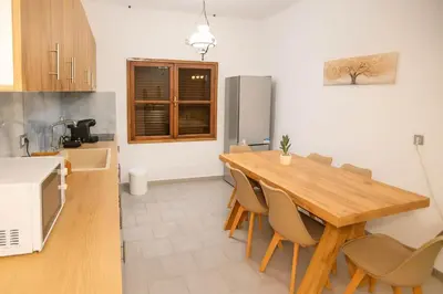 a kitchen with a wooden table and chairs in a kitchen at Sinani Villa - Garden Oasis with Private Pool in Kolimbia