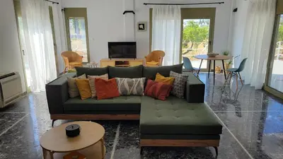 a living room with a green couch with colorful pillows at Aegean Villa & Garden in Faliraki in Faliraki