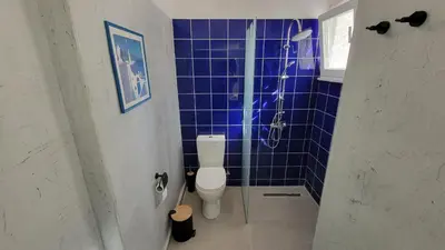 a blue tiled bathroom with a toilet and a shower at Aegean Villa & Garden in Faliraki in Faliraki