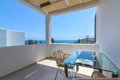 a balcony with a glass table and chairs at Villa Mariani in Kalathos