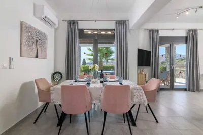 a dining room with a table with pink chairs at Villa Mariani in Kalathos
