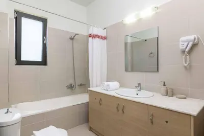 a bathroom with a sink and a tub and a mirror at Villa Mariani in Kalathos