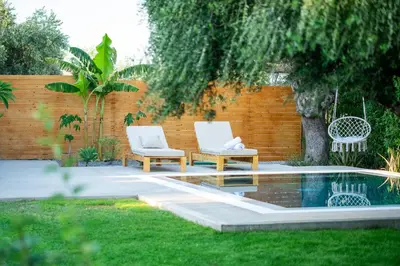 two white chairs sitting next to a swimming pool at Eléa Blu Pool & Garden in Afantou