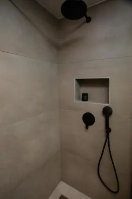 a bathroom with a shower with a blow dryer on the wall at Three Doors Villa Complex in Faliraki
