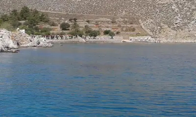 a body of water with a group of people on the shore at The Windmill in Symi