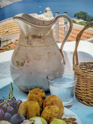 an old pitcher and a plate of fruit on a table at The Windmill in Symi