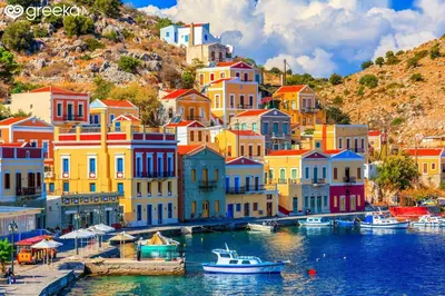 a group of colorful houses on a hill next to the water at The Windmill in Symi