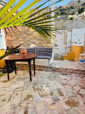 a table and a chair on a stone patio at Villa Kastrouna, with private heated jacuzzi in Symi