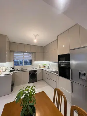 a kitchen with white cabinets and a table with a plant at Diagoras Suites in Rhodes Town