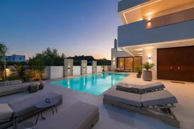 a swimming pool with lounge chairs and a house at Lanik Luxury Pool Villa in Afantou