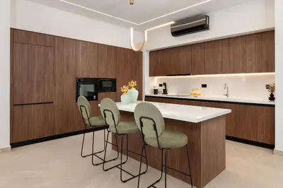 a kitchen with wooden cabinets and a bar with stools at Lanik Luxury Pool Villa in Afantou