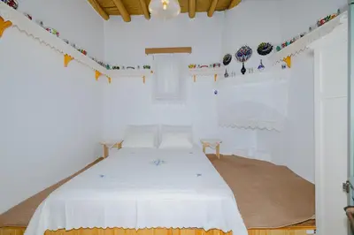 a white room with a bed with white sheets and decorations at Ikia Damianou Traditional House in Archangelos