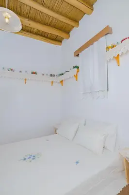 a bedroom with white walls and a bed with white sheets at Ikia Damianou Traditional House in Archangelos
