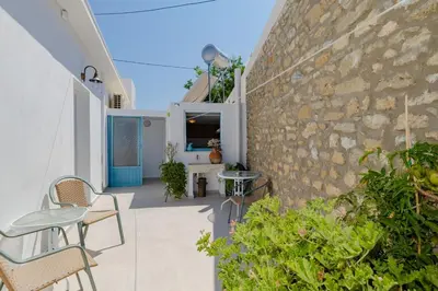 an outdoor patio with chairs and a stone wall at Statis House in Lardos