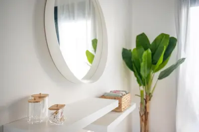 a white bathroom with a round mirror and a vase at Anna Maria Suite in Rhodes Town