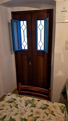 a bedroom with a door and two windows at Melitsaka in Nikiá