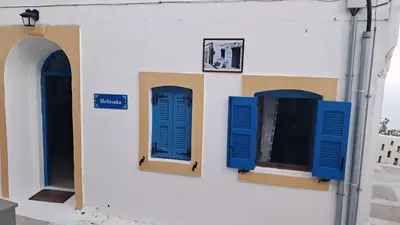 two blue shuttered windows on a white building at Melitsaka in Nikiá