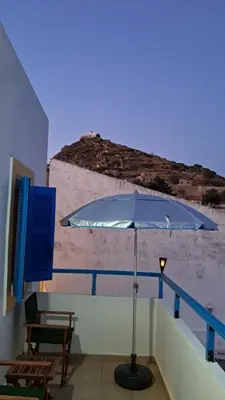 a blue umbrella on a balcony with a beach at Melitsaka in Nikiá
