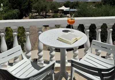 a table with a book and two chairs on a balcony at Le Soleil De Lindos - Luxury Villa with Swim Spa in Líndos