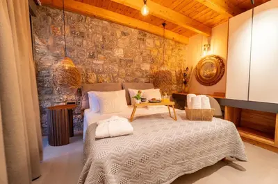 a bedroom with a bed and a stone wall at Etheras 2 - Holiday Apartments in Asgourou