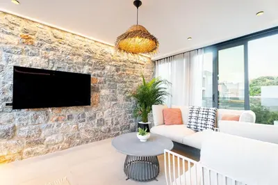 a living room with a stone wall with a tv at Etheras 2 - Holiday Apartments in Asgourou