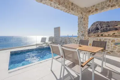a balcony with a table and chairs and a swimming pool at VILLA PAVA MARE sea view brand new 2025 in Vrachonisída touArchangélou