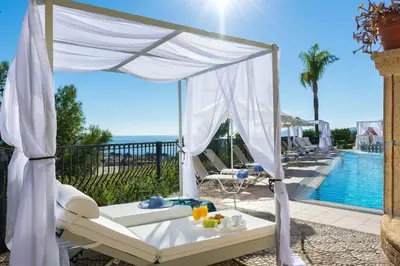 a canopy bed on a patio next to a pool at Pefkos View Suites & Maisonette in Pefki Rhodes