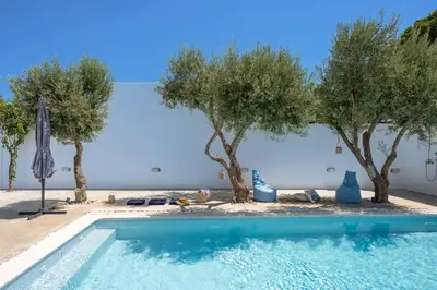 a swimming pool with trees next to a building at Gioiello Villa in Pefki Rhodes
