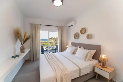a white bedroom with a bed and a balcony at Gioiello Villa in Pefki Rhodes