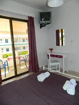 a room with a bed and a desk and a television at Roseberry Studios in Faliraki