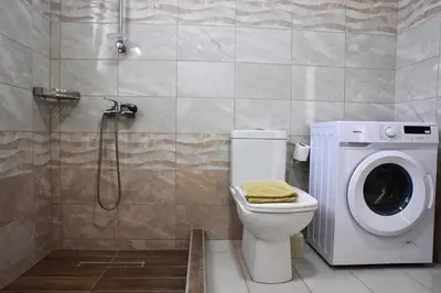 a bathroom with a washing machine next to a toilet at Roseberry Studios in Faliraki